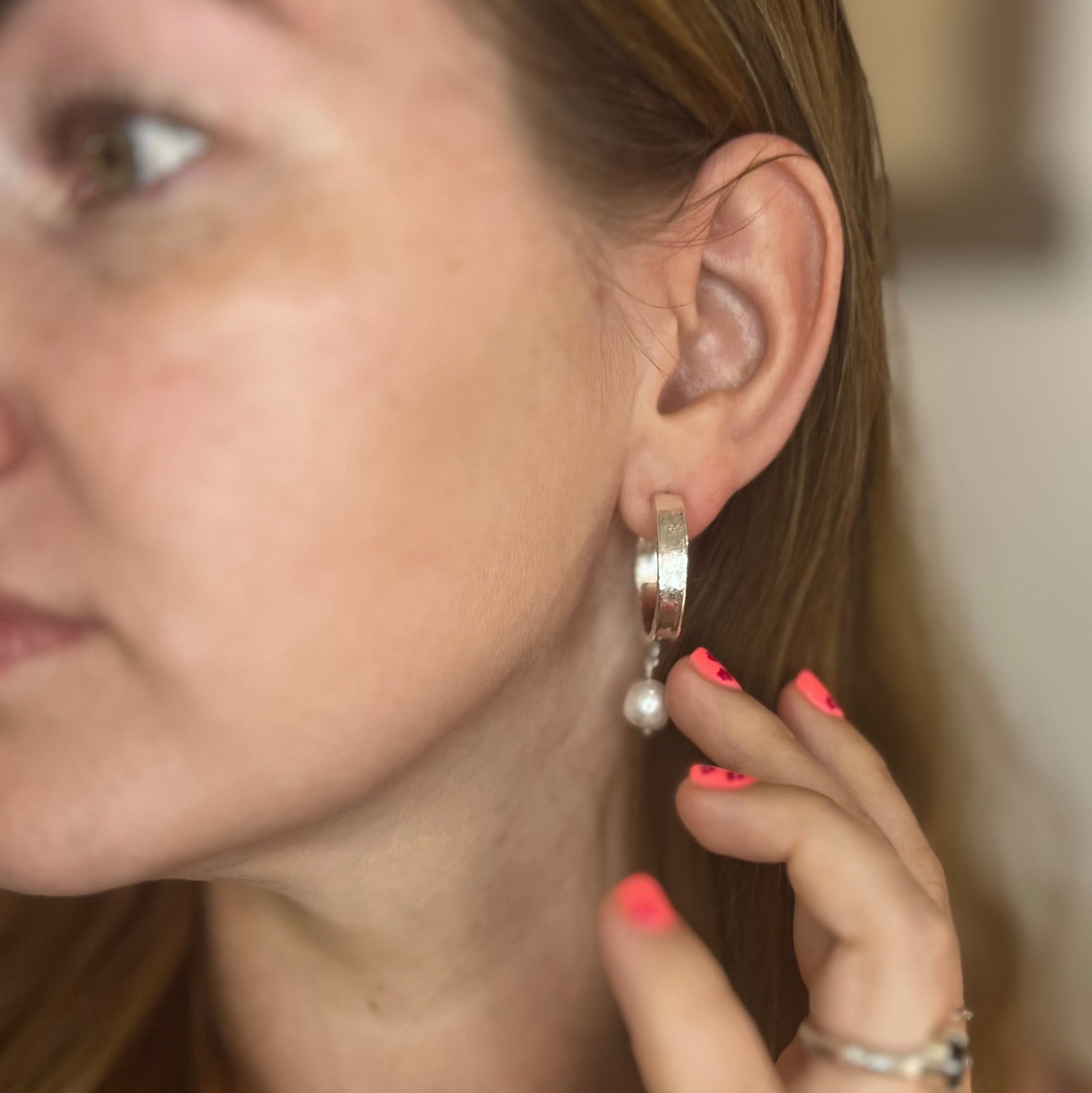 Close-up of a woman wearing silver hoop earrings with a blurred background