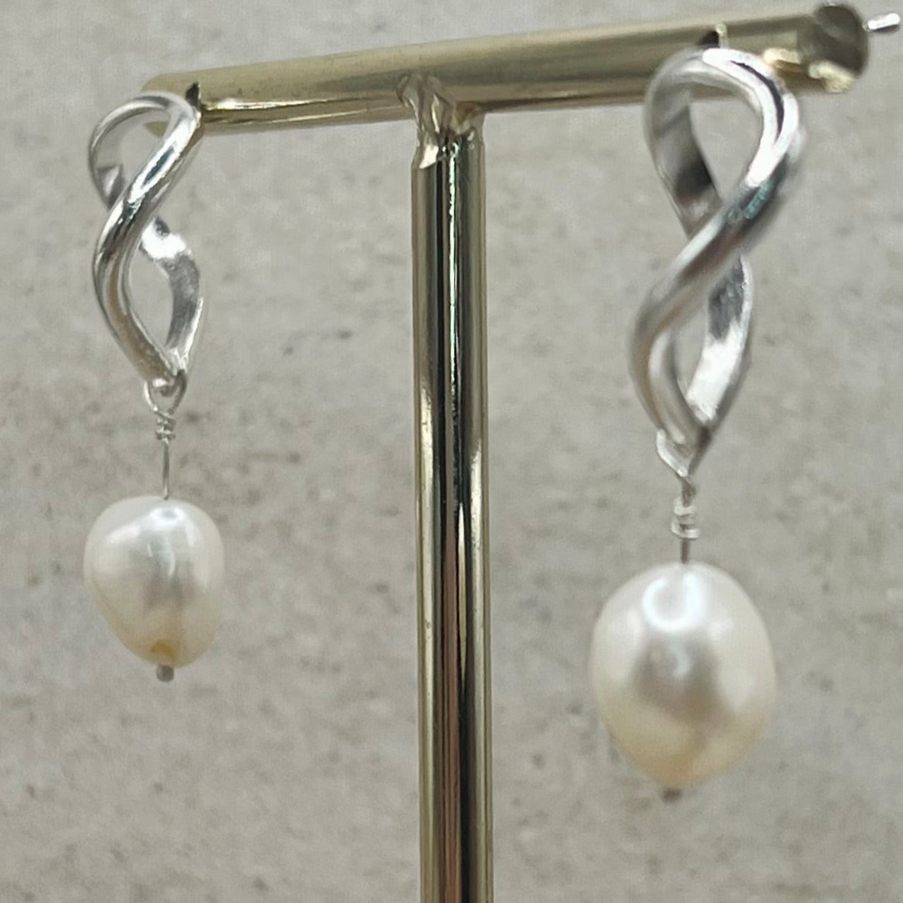Silver earrings with pearl drops on a gray background
