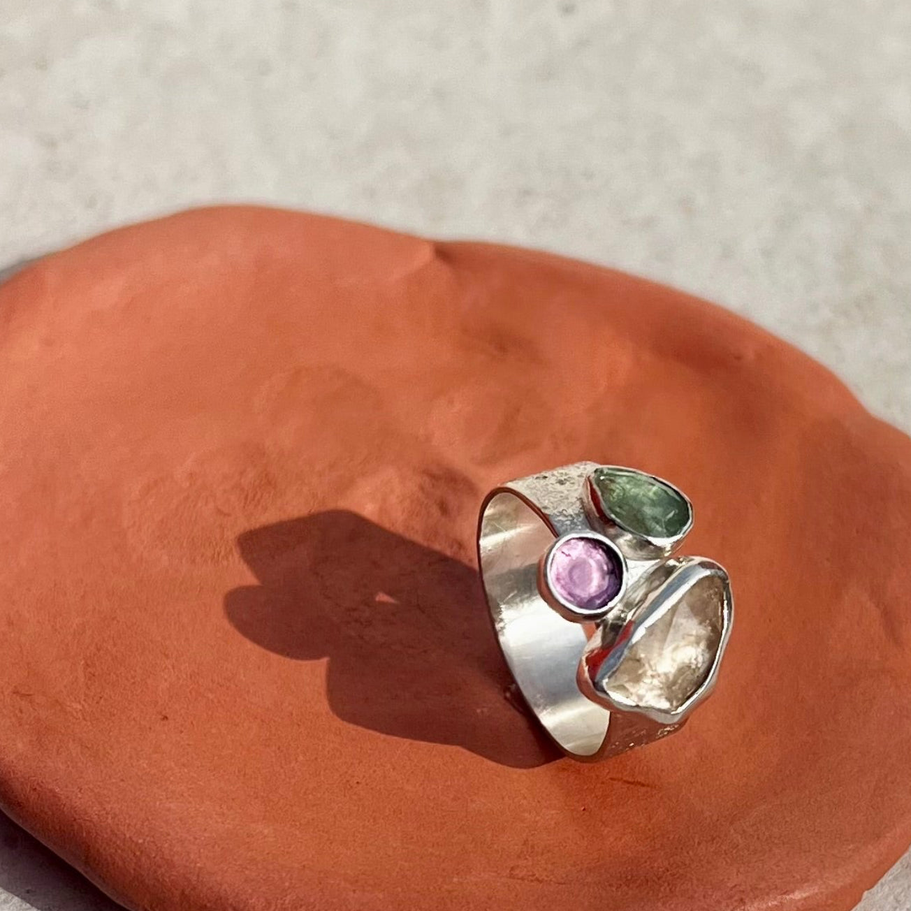 Silver ring with a pink and green gemstone on a red stone