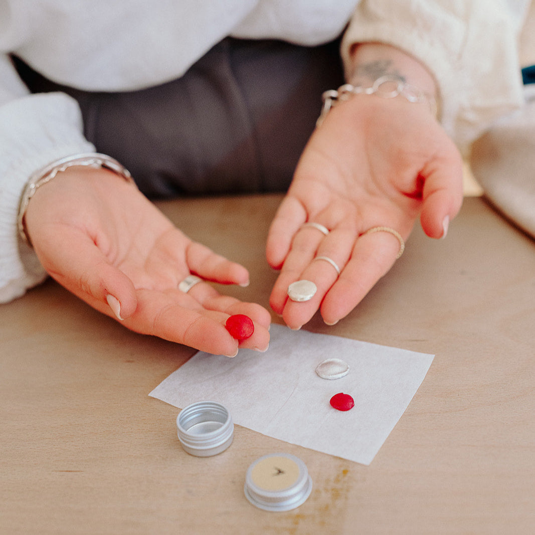 Person applying a small amount of cream to a cotton pad on a wooden surface.