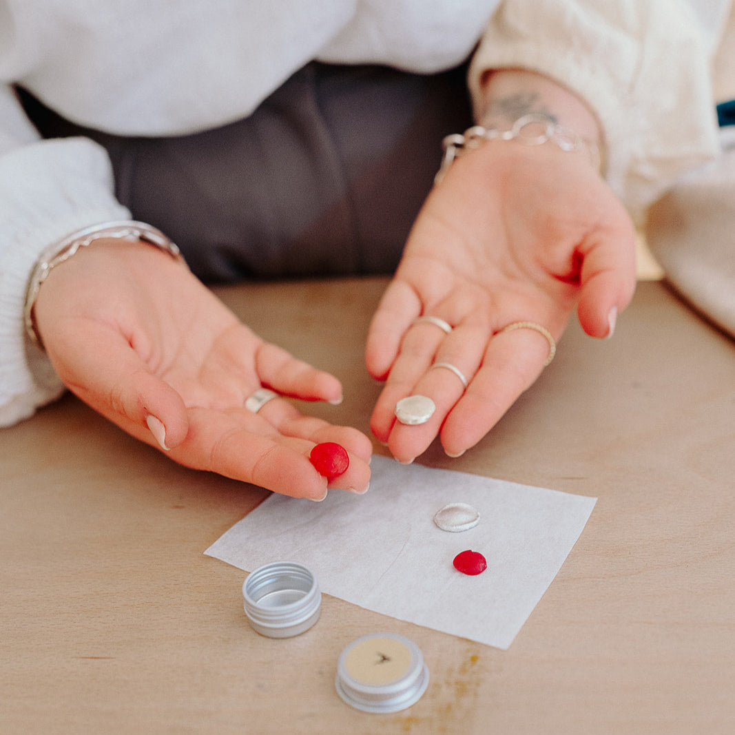 Person applying a small amount of cream to a cotton pad on a wooden surface.