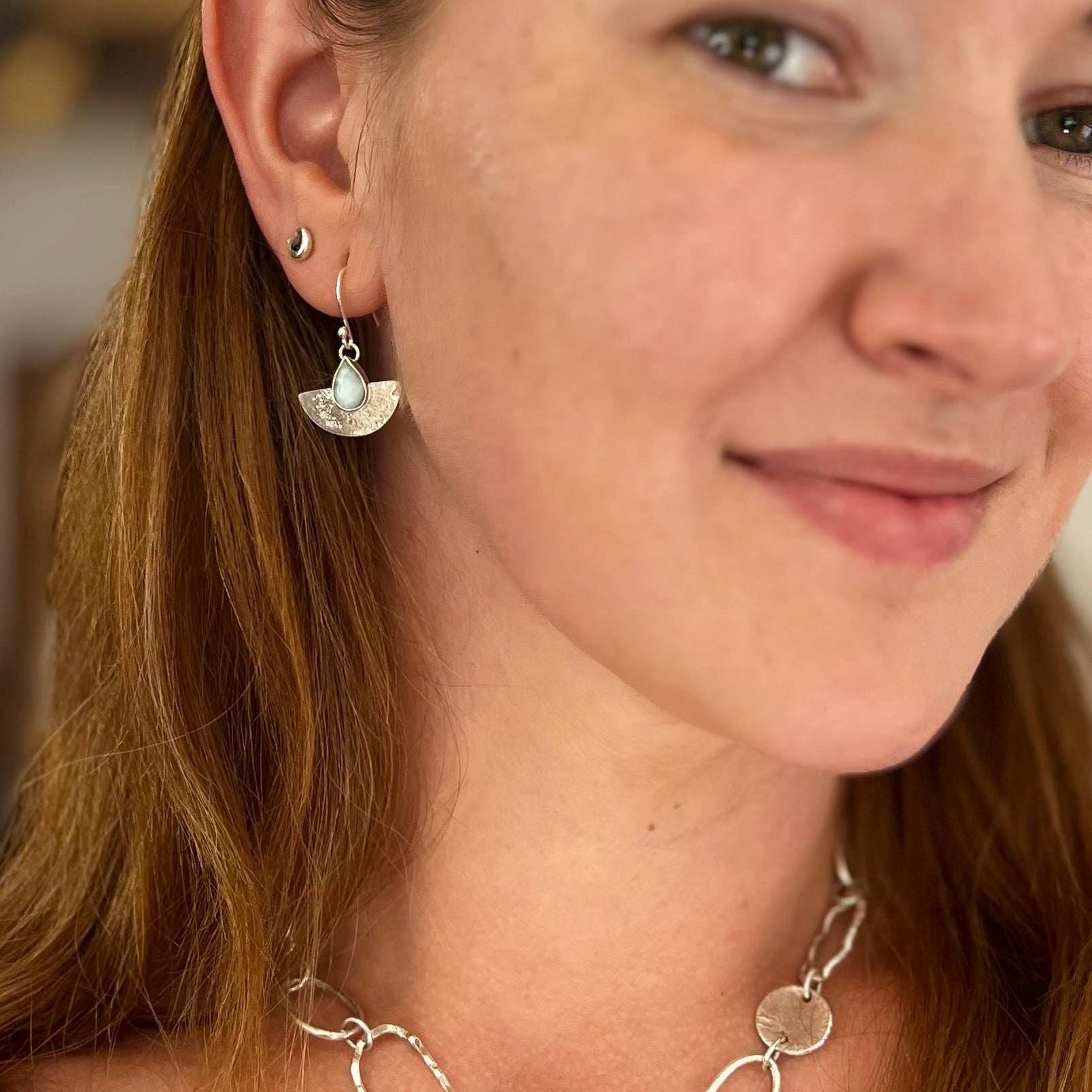 Close-up of a woman wearing a silver necklace and earrings.