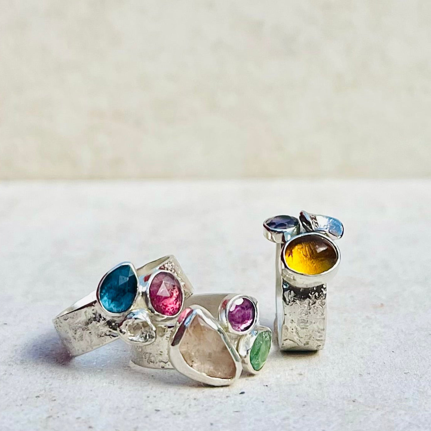 Set of silver rings with multicolored gemstones on a textured surface