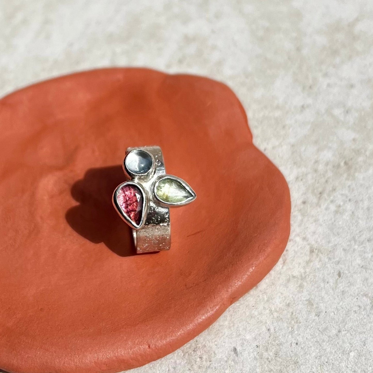 Silver charm with gemstones on a terracotta surface
