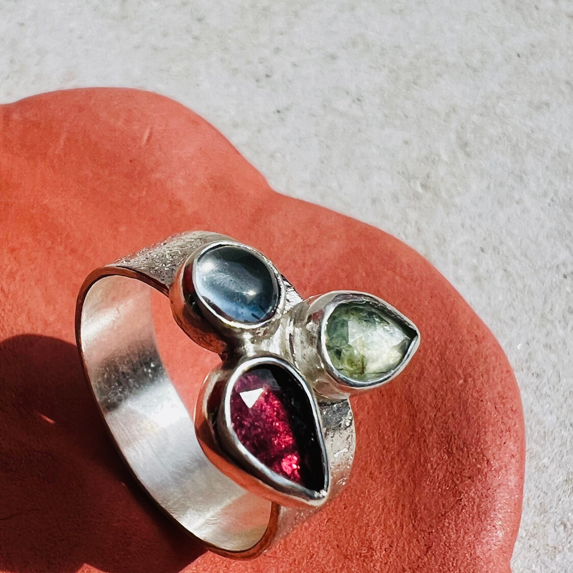 Silver ring with multicolored gemstones on a textured surface