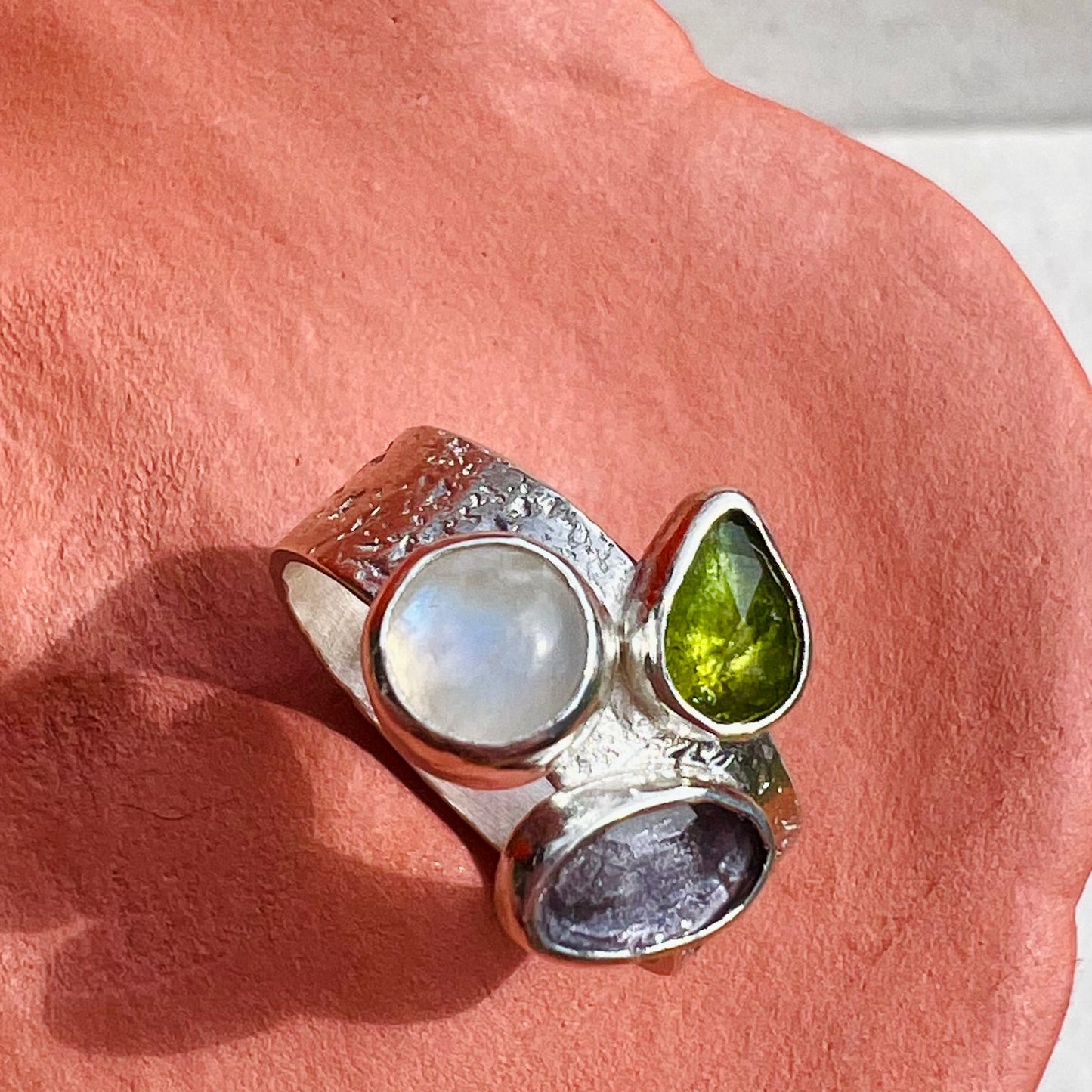 Silver ring with gemstones on a pink surface