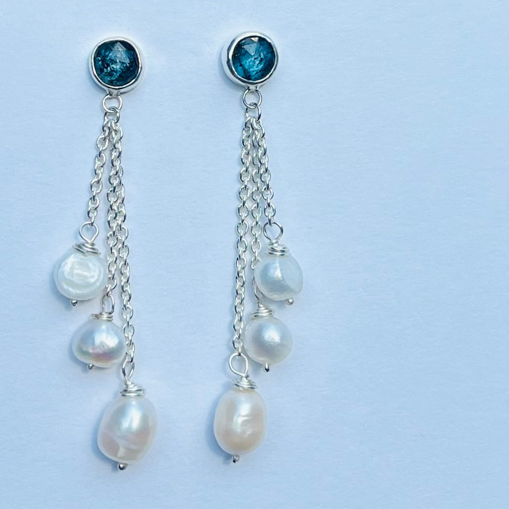 Pair of earrings with pearls and gemstones on a light blue background