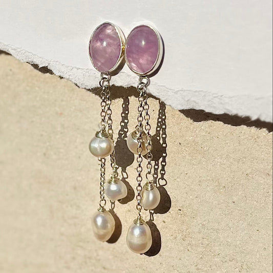 Earrings with pink gemstones and pearl drops on a textured surface