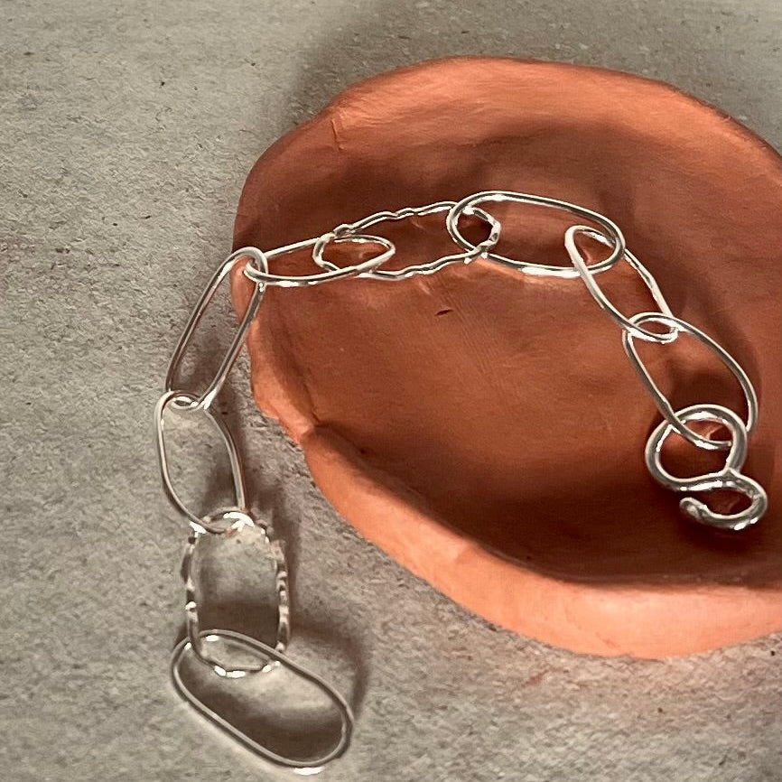 Silver chain on a terracotta pot against a gray background