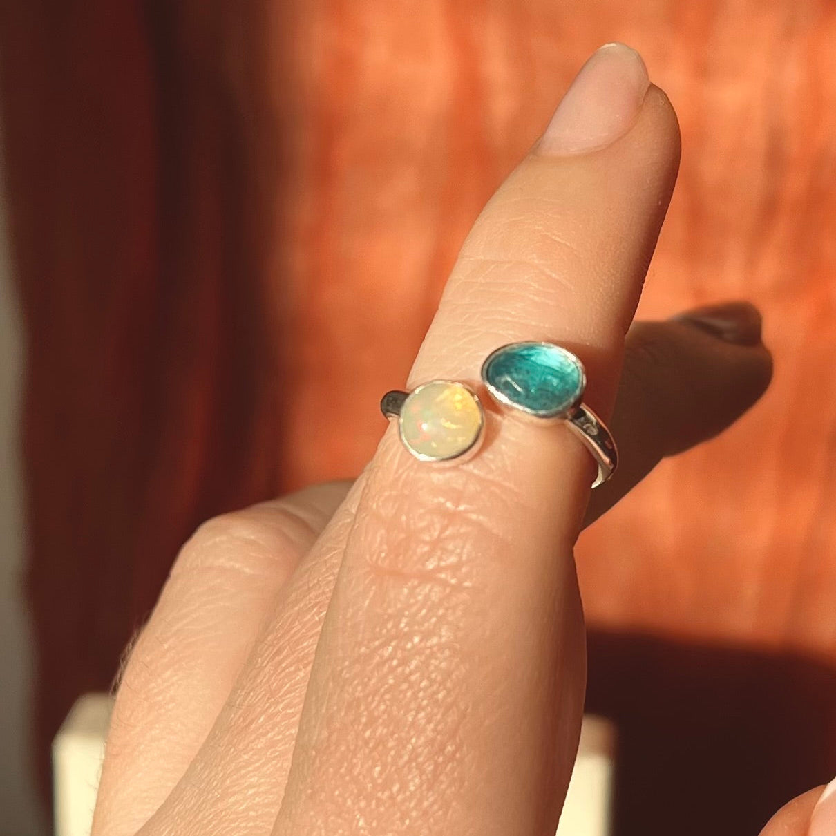 Close-up of a hand wearing a ring with a blue gemstone against a blurred background