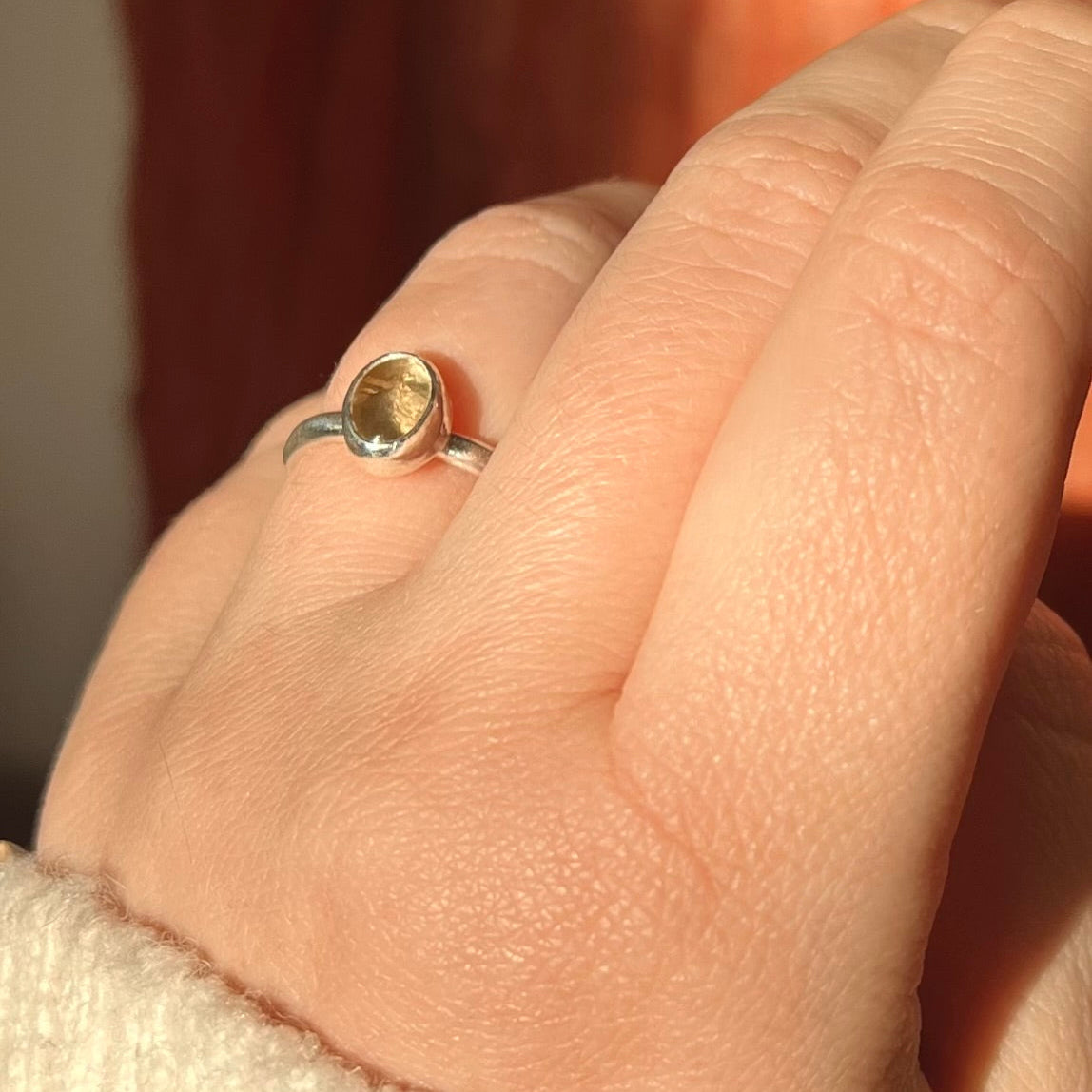 Close-up of a hand wearing a ring with a yellow gemstone.
