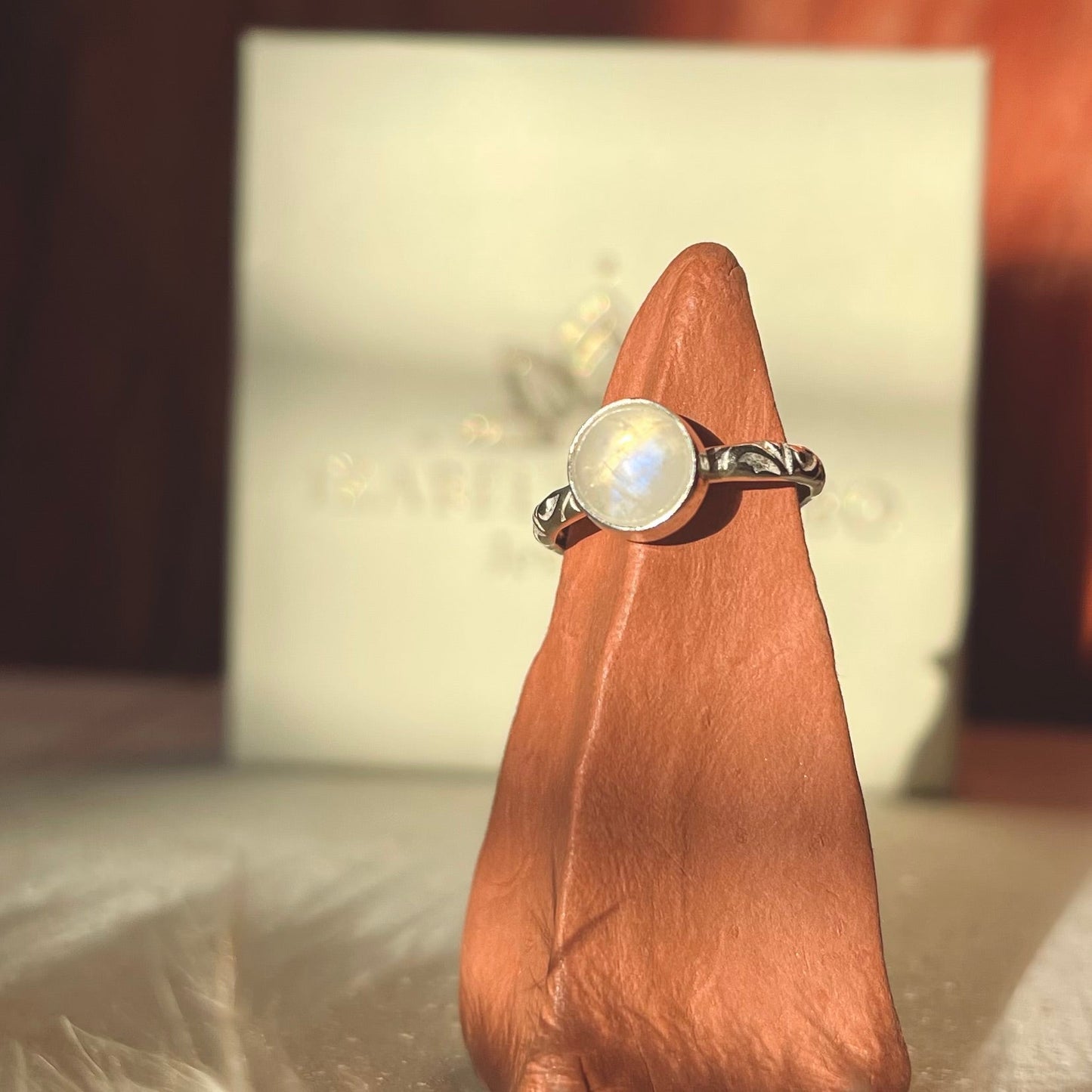 Ring with a moonstone on a wooden block against a blurred background