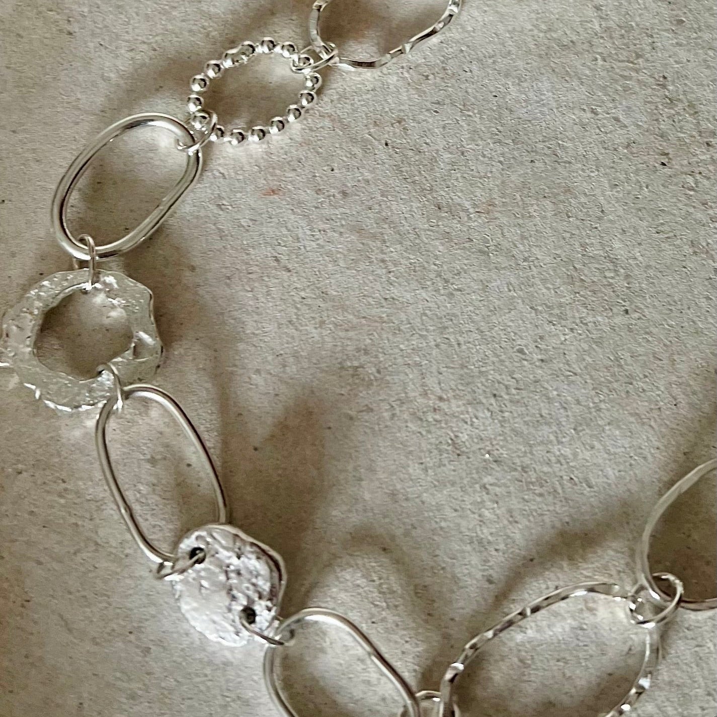 Silver chain necklace on a textured beige surface